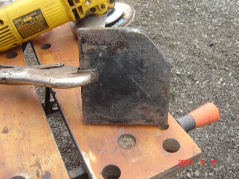 1993 Ford Bronco - Metal bracket and angle grinder on a workbench.
