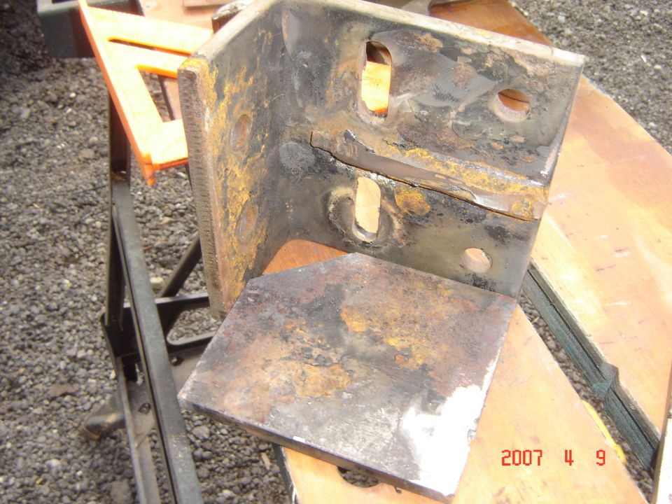 Rusted metal bracket with mounting holes, on a workbench