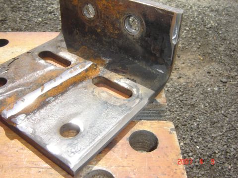 1993 Ford Bronco - Close-up of a heavily rusted metal bracket, showing wear and bolt holes.