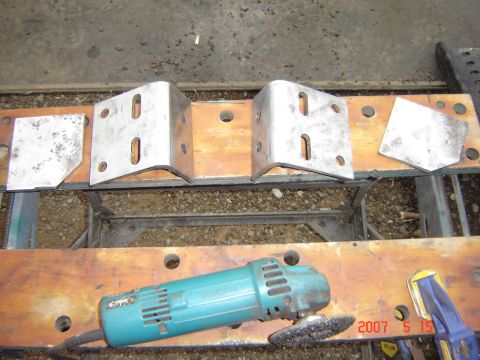 1993 Ford Bronco - Metal brackets and a grinder are laid out on a workbench, suggesting a repair or fabrication project.