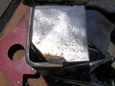 1993 Ford Bronco - A close-up view of a metal component that has been welded, resting on a wooden surface with a red magnetic clamp nearby.