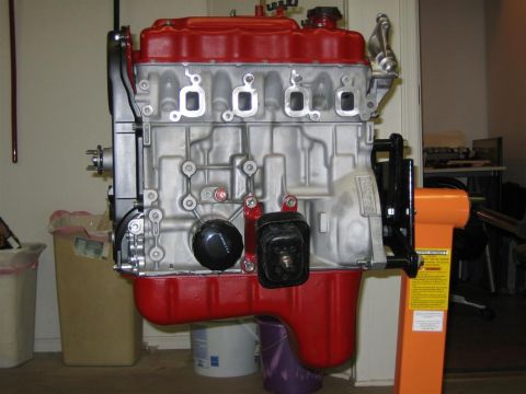 1987 Suzuki Samurai - Engine block on an orange stand, with red accents on the oil pan and valve cover.