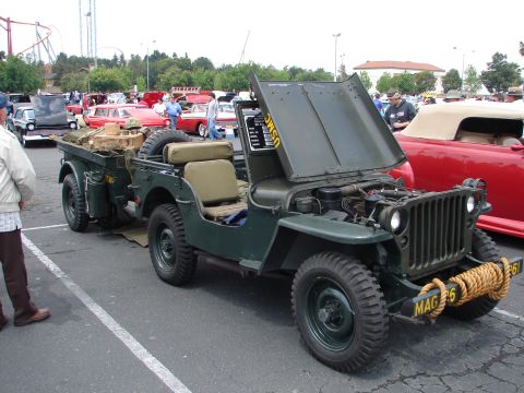 1992 Ford Taurus - This olive drab jeep, marked USMC, is displayed with its hood open and is towing a trailer. Other vehicles are visible in the background.