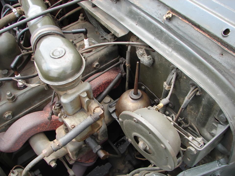 Engine compartment detail showing carburetor, spark plug wires, and an oil can