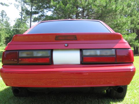 1967 Ford Mustang - This red Ford Mustang features a rear spoiler and a distinctive white stripe across its trunk panel.