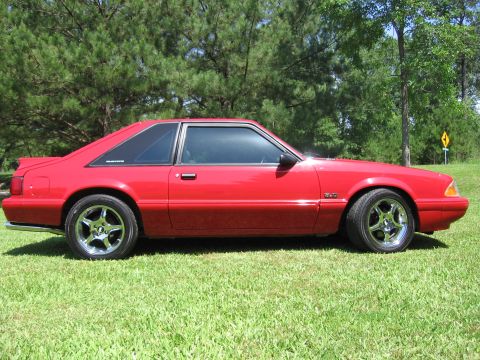 1967 Ford Mustang - This red coupe, identified as a 1993 Ford Mustang, is viewed from its side profile.