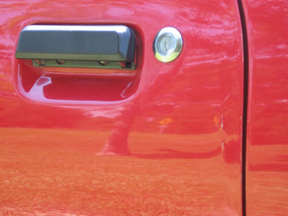Close-up of a red car door handle and keyhole