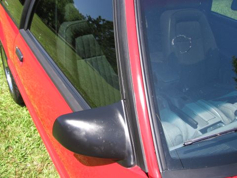 1967 Ford Mustang - Close-up view of a red car's side door, mirror, and interior.