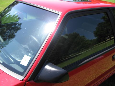 1967 Ford Mustang - The side profile of a red car is visible, with trees and grass reflected in the windows.