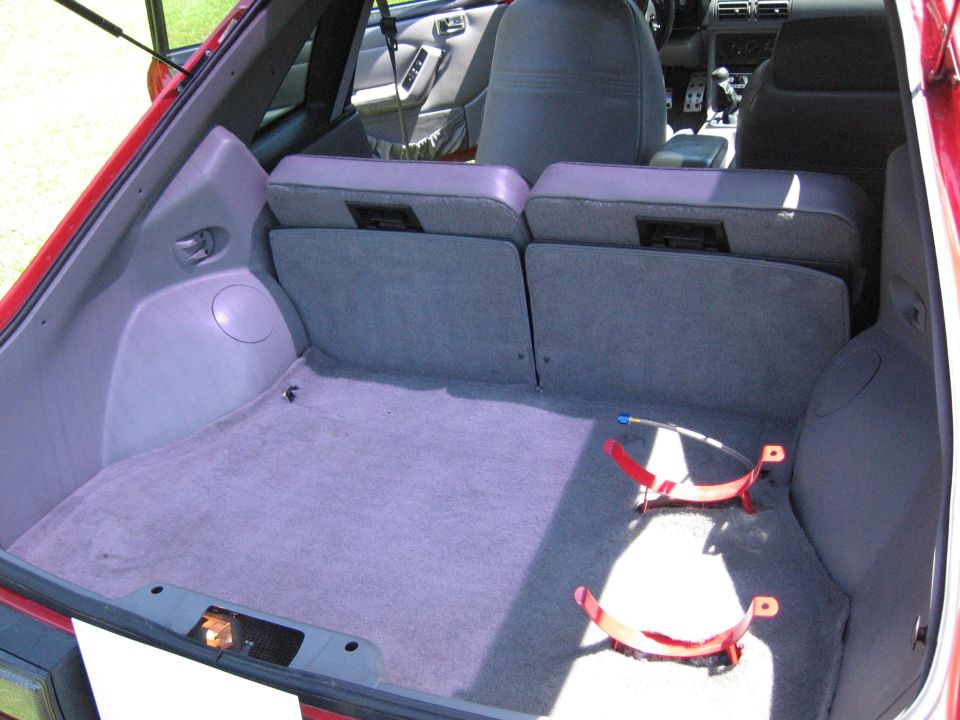 Red hatchback interior showing folded rear seats and carpeted cargo area with red brackets