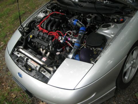 1993 Ford Probe - Engine bay of a silver car a turbocharger, aftermarket intake, and red spark plug wires.