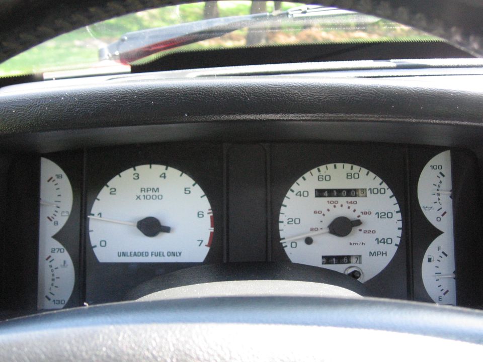 Car dashboard with white gauges including tachometer, speedometer, fuel, and temperature. Odometer reads 41003