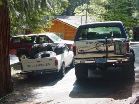 1986 Ford Bronco - A lifted Ford Bronco and a Volkswagen pickup truck are parked side-by-side in a driveway.