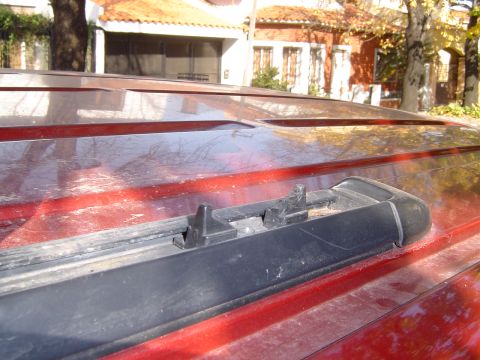 1996 Ford Explorer - The roof of a red SUV shows a close-up view of its roof rack system and the surrounding body panels.