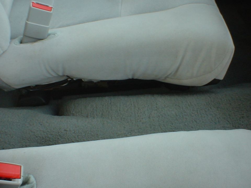 Gray cloth car seats and carpet with seat belt buckles visible between front and rear seats