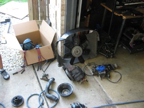 1979 Ford Bronco - Various automotive parts are spread across the concrete floor of a garage.
