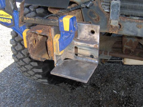 1993 Ford Bronco - A custom-fabricated bracket is attached to a vehicle's front bumper assembly using an Irwin Quick-Grip clamp, with a large tire visible.