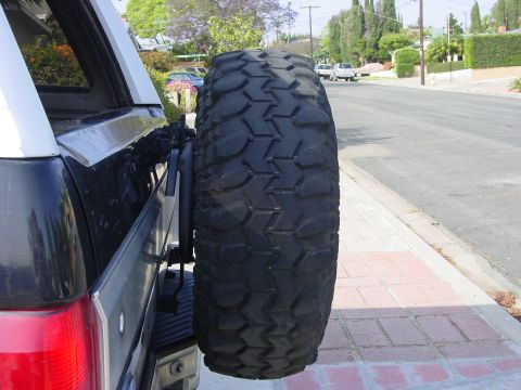1994 Ford Bronco - Spare tire mounted on the rear carrier of a vehicle, seen from the side.