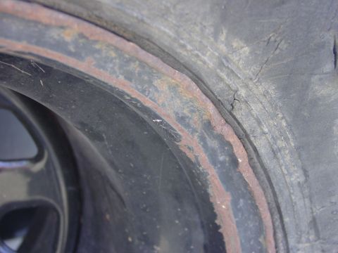 1994 Ford Bronco - This image shows a close-up view of a heavily rusted wheel rim and tire, with visible wear and tear.