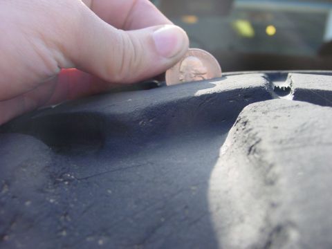 1994 Ford Bronco - A penny is used to check the tread depth of a tire, with the Supermotors.net logo in the corner.