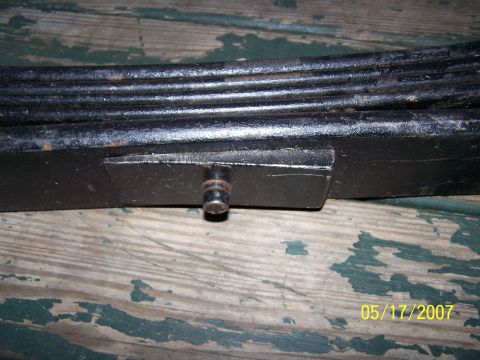 1979 Ford F-150 - A close-up view of a vehicle leaf spring, showing its layered metal construction and a securing bolt.