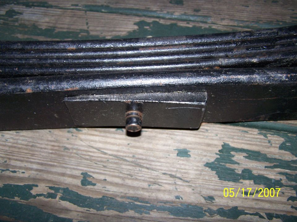Black metal leaf spring with a bolt protruding from a bracket