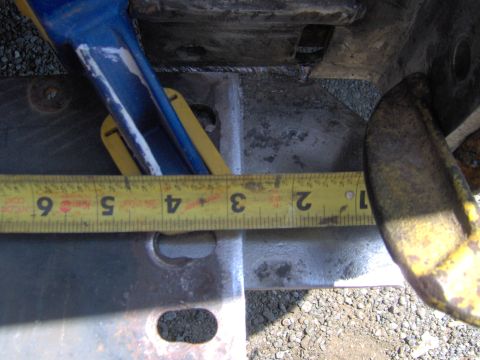 1993 Ford Bronco - A yellow measuring tape is shown against a metal component, with markings indicating measurements.