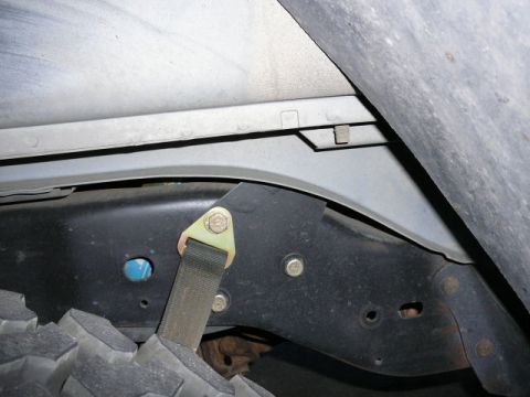 1988 Ford Bronco - Underside view of a vehicle's frame, tire, and a strap attached to the frame.