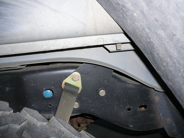 close-up of vehicle frame, tire, and strap