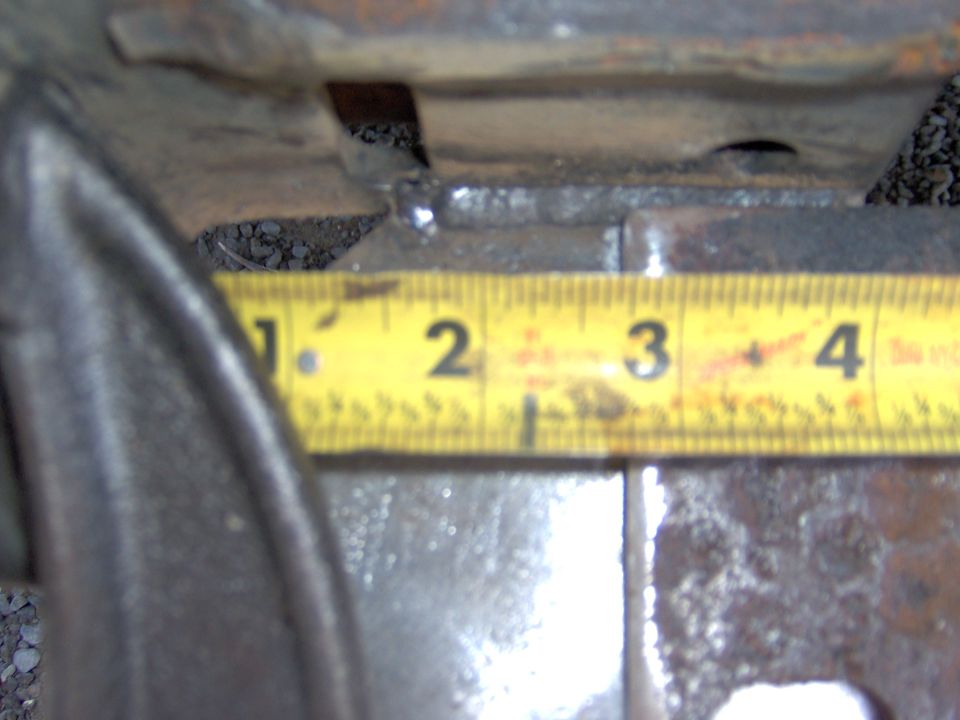 Close-up of a metal part with a yellow measuring tape showing approximately 2.5 inches