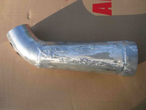 1997 Lincoln Town Car - A bent metal air intake tube with visible, rough welds is shown against a cardboard background.