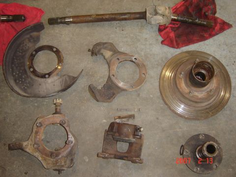 1993 Ford Bronco - Various vehicle suspension components are spread out on a concrete surface, suggesting a repair or rebuild process.