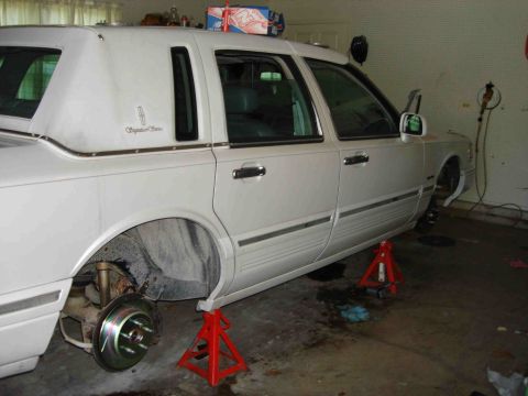 1997 Lincoln Town Car - White 1997 Lincoln Town Car undergoing brake maintenance in a garage.