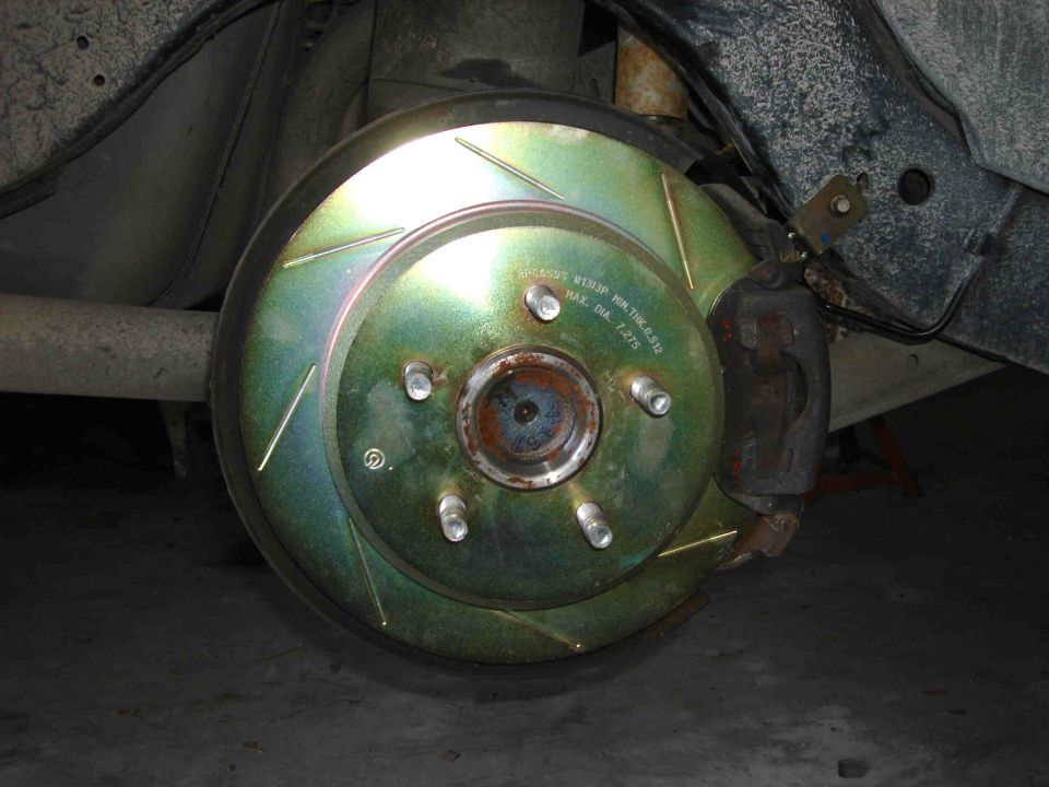 Close-up of a slotted brake rotor and caliper on a vehicle's wheel assembly