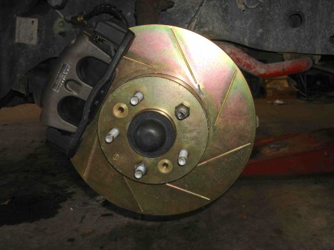 1997 Lincoln Town Car - Close-up view of a vehicle's brake system, showing a gold slotted rotor and caliper.