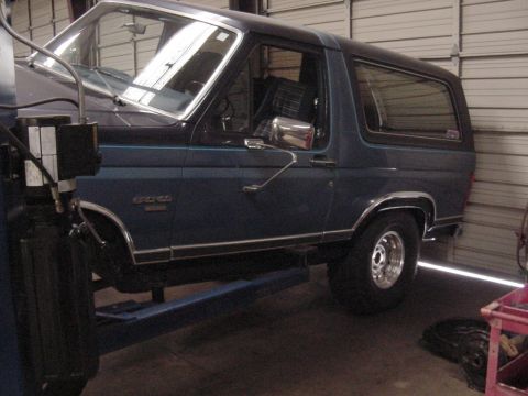 1984 Ford Bronco - Side view of a blue 1984 Ford Bronco, lifted for service.