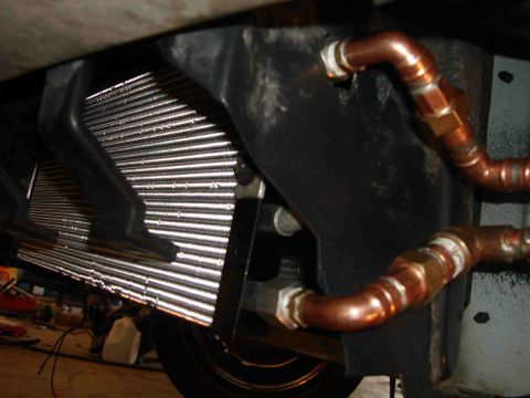 1997 Lincoln Town Car - Close-up of an engine oil cooler and its copper plumbing, mounted to a vehicle's chassis.