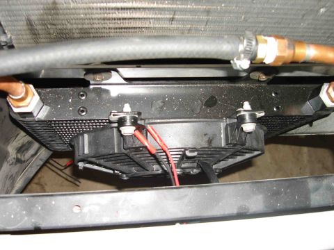 1997 Lincoln Town Car - Close-up view of an aftermarket transmission cooler with an integrated fan, mounted in front of a radiator.