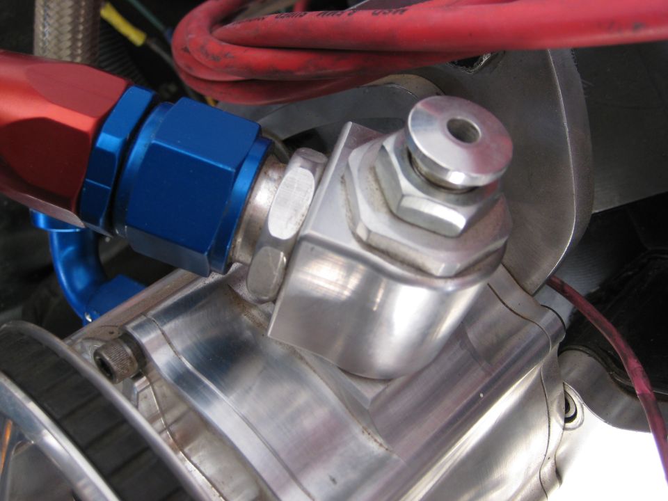 Close-up of a fuel line fitting on an engine with red and blue anodized aluminum parts