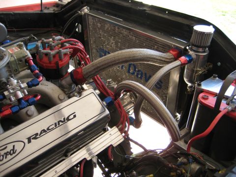 1979 Ford Bronco - Close-up view of an engine bay Ford Racing valve covers and braided hoses connected to the radiator.