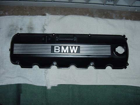 1989 BMW 3 Series - A black BMW valve cover with silver stripes and the BMW logo is shown, likely a replacement part.
