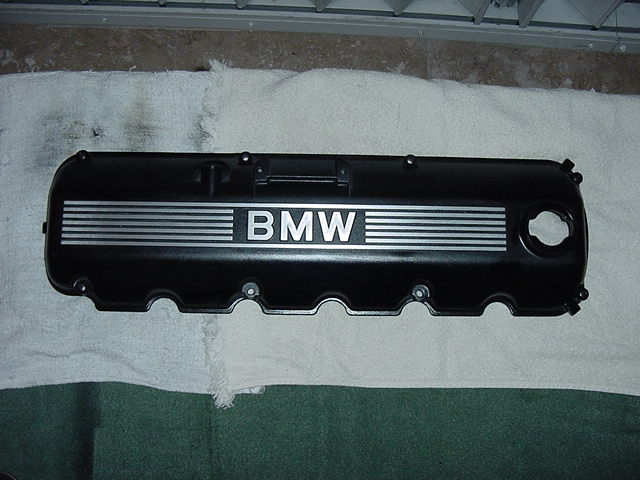 Black BMW valve cover with silver stripes and BMW logo
