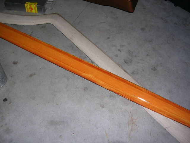 Orange-stained wood trim piece and a lighter wood piece on a concrete floor