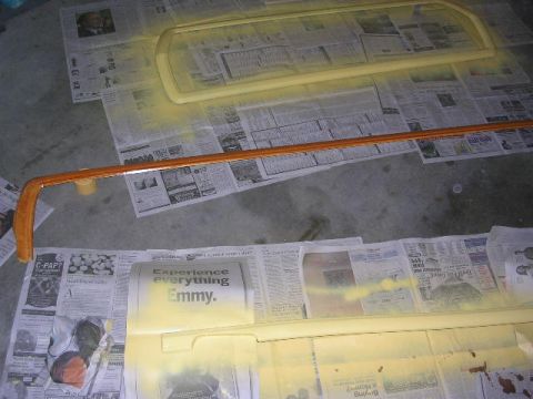1975 Ford Ranchero - Car trim pieces are laid out on newspapers and being painted yellow, with one piece showing a woodgrain finish.