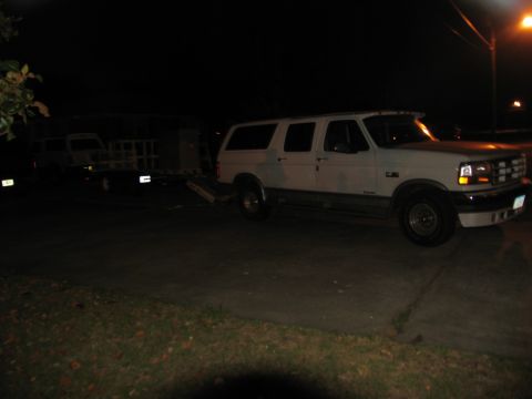 1988 Ford C-350 (Centurion Conversions) - Ford F-Series truck towing a trailer with another vehicle on it at night.