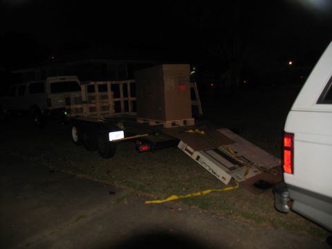 1988 Ford C-350 (Centurion Conversions) - A trailer is loaded with cargo at night, with a white vehicle nearby.