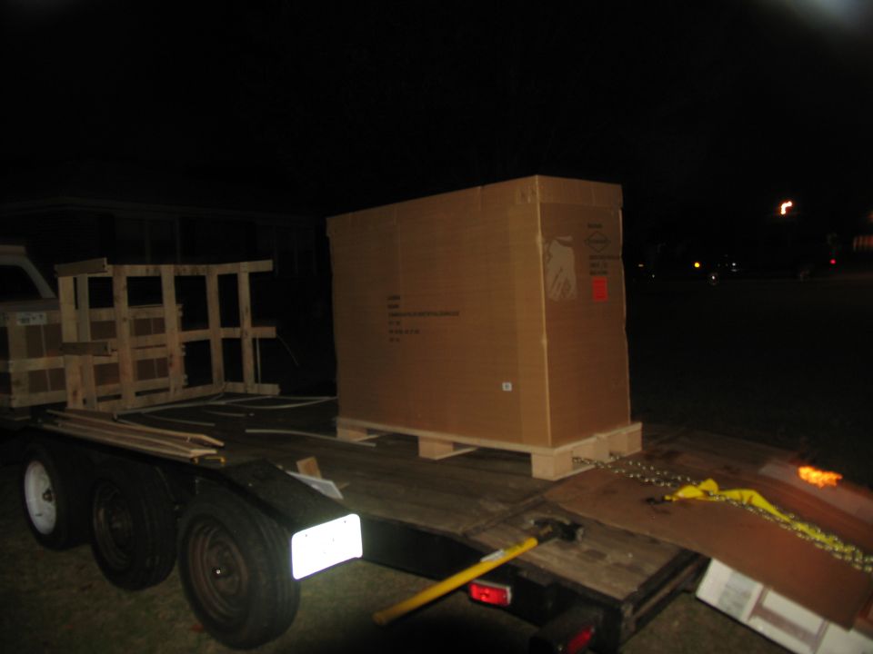 Trailer at night carrying a large cardboard box on a pallet and wooden crates