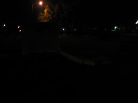 1988 Ford C-350 (Centurion Conversions) - A dimly lit scene at night, with streetlights casting a glow on blurred trees and pavement.