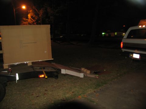 1988 Ford C-350 (Centurion Conversions) - A van with a camper shell is parked at night next to a trailer loaded with a large cardboard box.