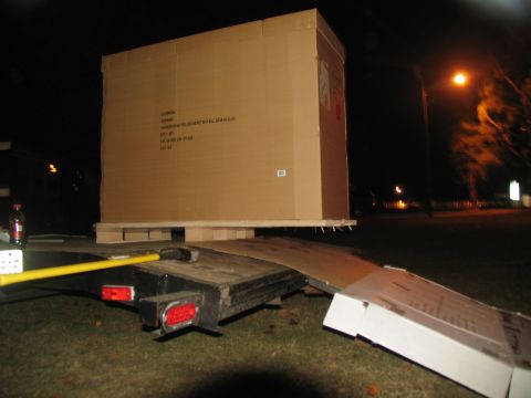 1988 Ford C-350 (Centurion Conversions) - Large cardboard box being loaded onto a trailer at night.